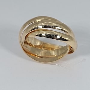Peut inclure: Une bague en or poli composée de trois anneaux entrelacés qui se chevauchent pour créer une forme arrondie continue. La surface métallique est lisse et réfléchissante, affichant un ton jaune chaud sur toute la structure circulaire.