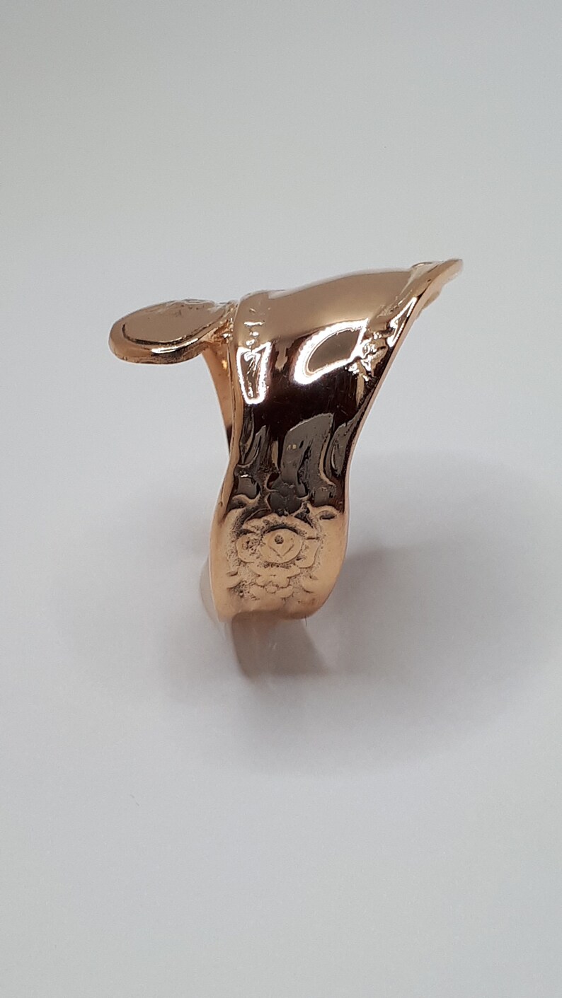 May include: A gold-toned finger ring with a decorative design. The ring is made of metal and has a smooth, polished finish.