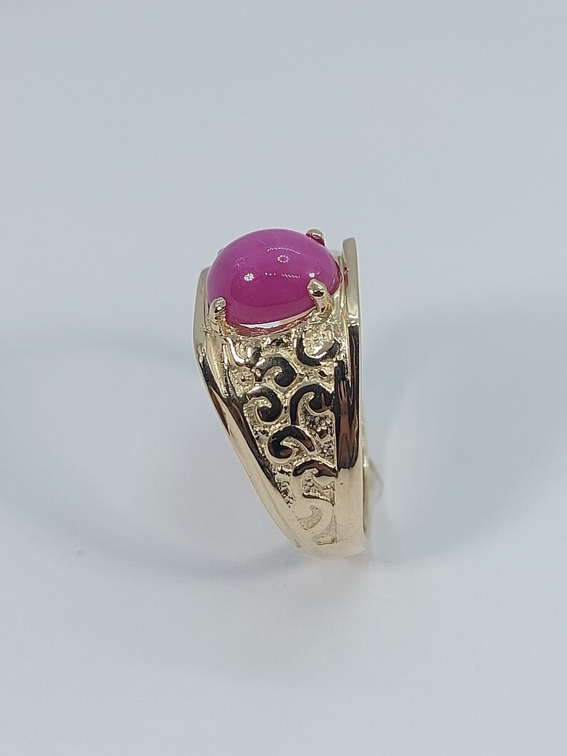 Op de afbeelding: Een gouden ring met een roze ovale edelsteen gezet in een filigraan ontwerp.