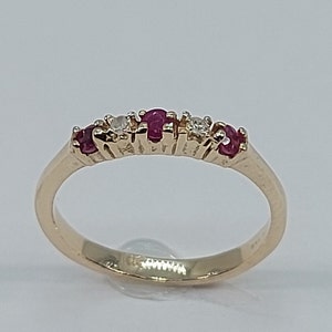 May include: A gold band ring with alternating red rubies and clear diamonds.
