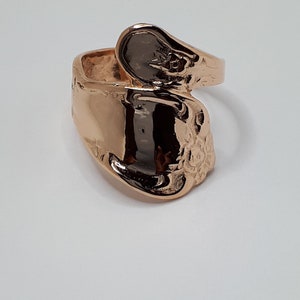 May include: A rose gold spoon ring with a floral design. The ring is made from a repurposed spoon.