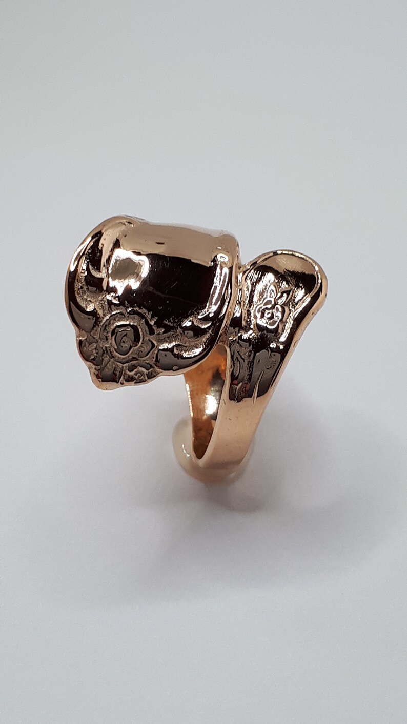 May include: A gold-toned ring with a detailed floral design. The ring is open and designed to fit on the finger.