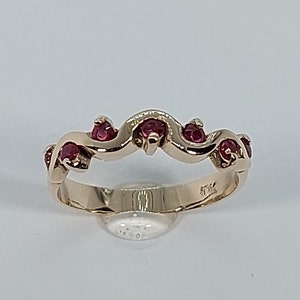 May include: A gold band ring with a wavy design and red gemstones.