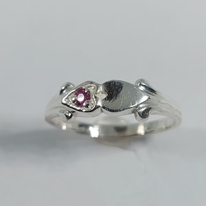 Peut inclure: Une bague en argent avec un motif en forme de cœur et une petite pierre précieuse rose au centre.