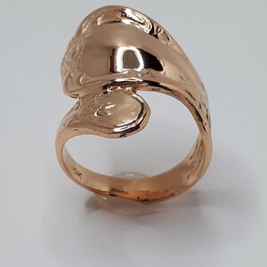 May include: A gold-toned ring with a unique, twisted design. The ring is marked "10K" on the inside.