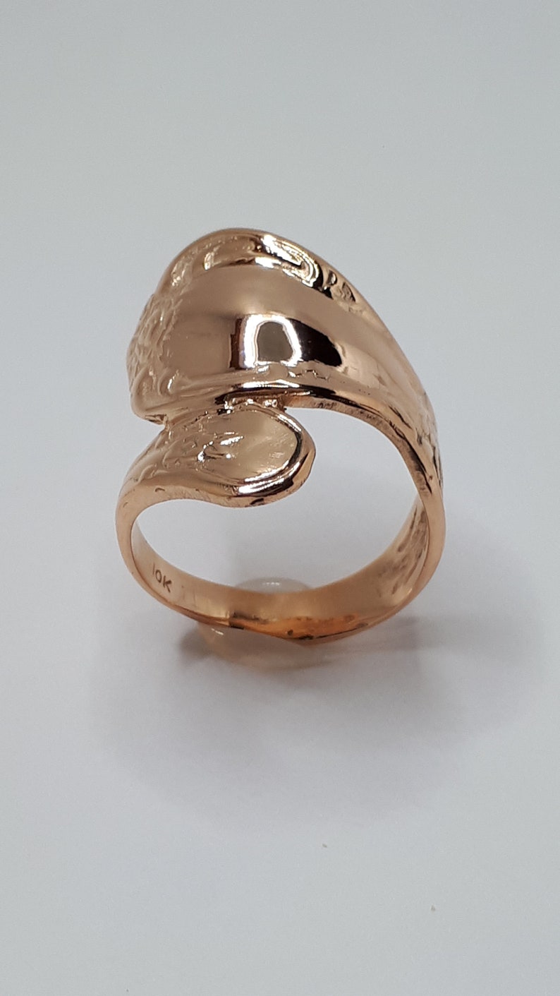 May include: A gold-toned ring with a unique, twisted design. The ring is marked "10K" on the inside.