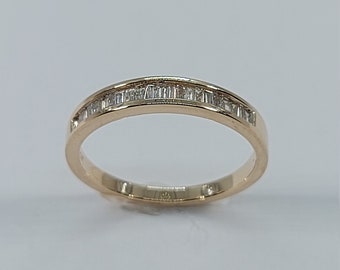 May include: A gold band ring with a row of small, rectangular diamonds set in the band.