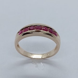 May include: A gold band ring with a row of red ruby stones set in the band.