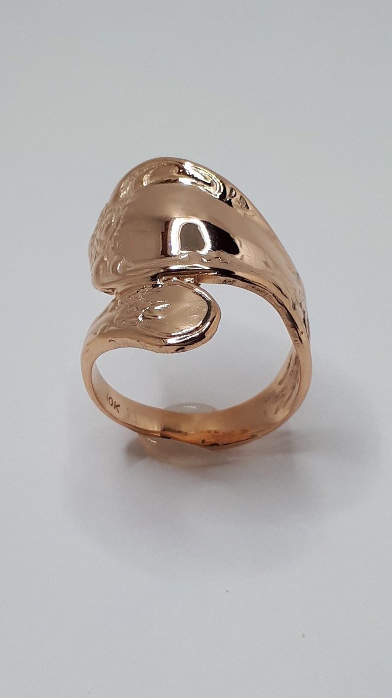 May include: A gold-toned ring with a unique, wave-like design. The ring is marked with "10K" on the inside band.
