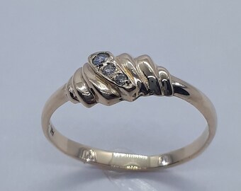 Op de afbeelding: Een gouden ring met een gedraaid ontwerp en drie kleine diamanten die in het midden zijn gezet.