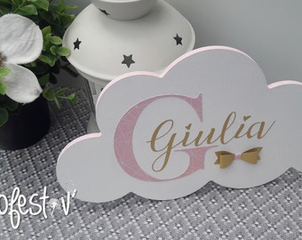 May include: A white wooden cloud-shaped sign with a pink and gold "G" and the name "Giulià" in gold lettering. A gold bow is attached to the sign.