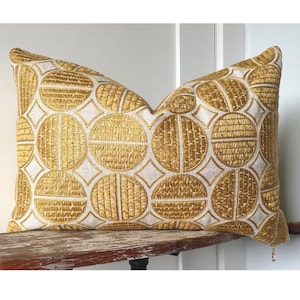 Funda de almohada circular bordada: medallón gráfico color mostaza, aspecto lino.