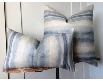 May include: Two decorative throw pillows with a blue and white watercolour stripe pattern. The pillows are made of a soft, textured fabric and are perfect for adding a touch of style to any room.
