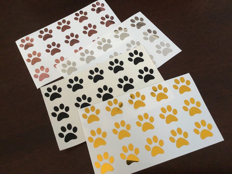 May include: Four sheets of paw print stickers in gold, black, silver, and rose gold. Each sheet has 16 paw prints.