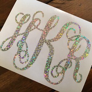 May include: A white vinyl sticker with a silver glitter monogram of the letters "LRB" in a cursive font.