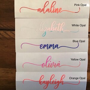 May include: Five vinyl stickers with different names written in cursive script. The names are Adaline, Elizabeth, Emma, Olivia, and Kayleigh. Each sticker has a different coloured background, including pink, white, blue, yellow, and orange.