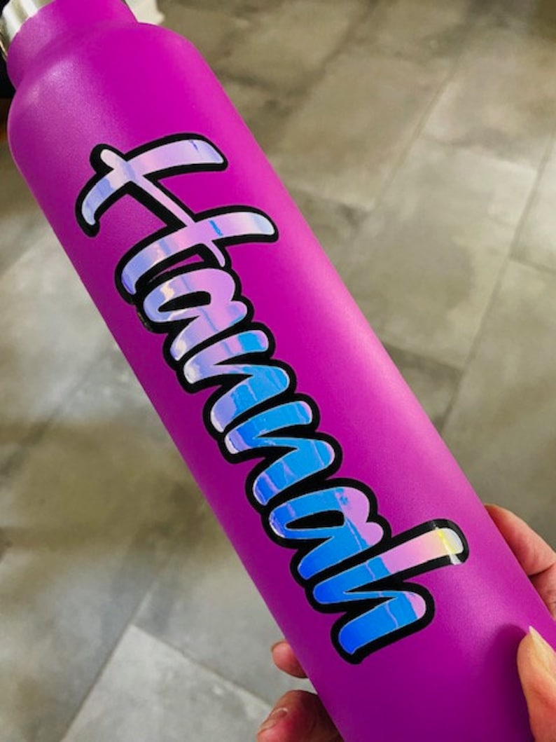 May include: A purple water bottle with a holographic sticker that says "Hawaii" on it.