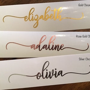 May include: Three white labels with different names written in gold, rose gold, and silver chrome lettering. The names are "elizabeth", "adaline", and "olivia".