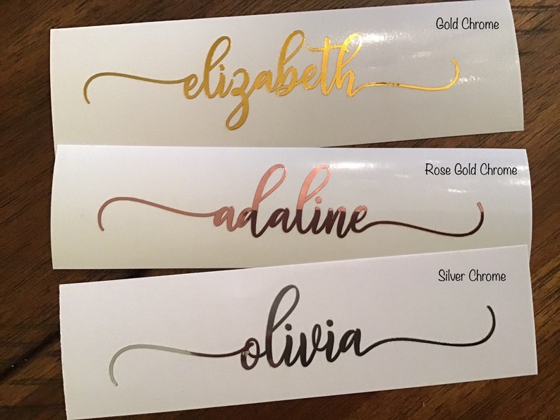 May include: Three white labels with different names written in gold, rose gold, and silver chrome lettering. The names are "elizabeth", "adaline", and "olivia".