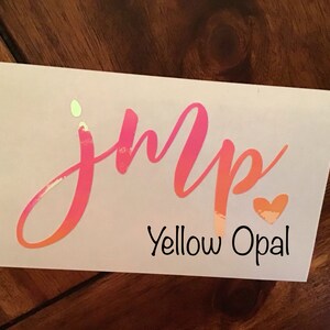 May include: A pink and orange iridescent vinyl decal with the word "jump" in cursive lettering and a small heart. The text "Yellow Opal" is printed below the word "jump".