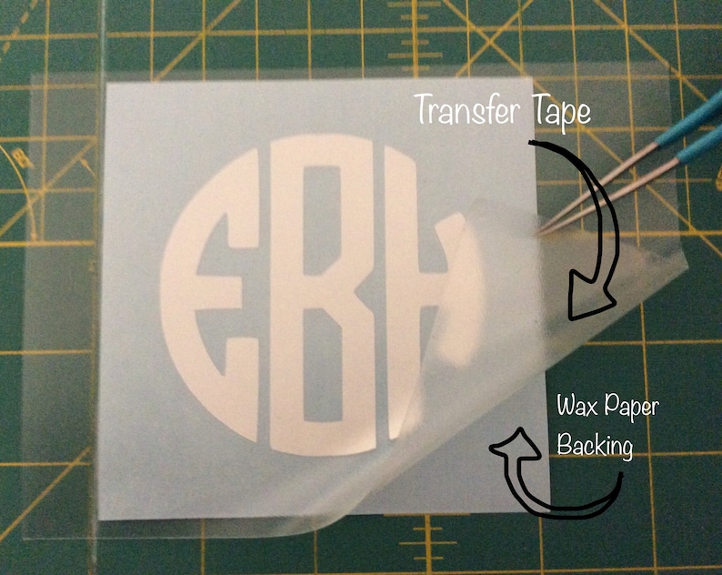 May include: A white vinyl monogram sticker with the letters "EBH" in a circle, on a clear transfer tape sheet. The transfer tape is being peeled off of the wax paper backing.