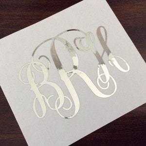 May include: Silver monogram decal with the letters "BRS" in a cursive font.