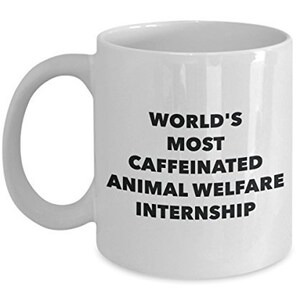 May include: White ceramic coffee mug with black text that reads "World's Most Caffeinated Animal Welfare Internship".
