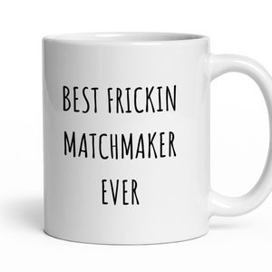 May include: White ceramic coffee mug with black text that reads "Best Frickin Matchmaker Ever".