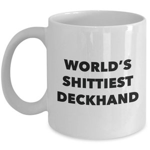 May include: White ceramic coffee mug with black text that reads "World's Shittiest Deckhand".