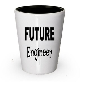 Op de afbeelding: Een wit keramiek shotglas met een zwarte rand. Het glas heeft de tekst "FUTURE Engineer" in zwart gedrukt.