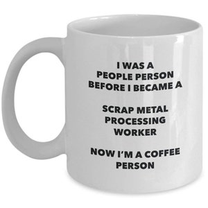 May include: White ceramic coffee mug with black text that reads: "I was a people person before I became a scrap metal processing worker. Now I'm a coffee person."