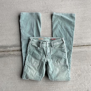 May include: A pair of green corduroy pants with a wide leg and a button fly. The pants have two large pockets on the front and a small pocket on the back.