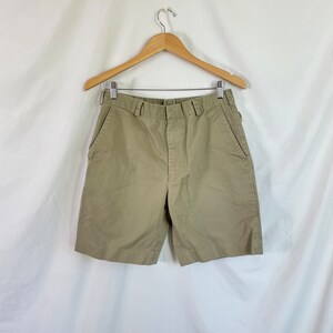 May include: A pair of khaki shorts with a button and zipper closure. The shorts have two front pockets and two back pockets.