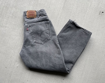 May include: Gray denim jeans with a faded wash and a Levi's patch on the back. The jeans have a straight leg and a relaxed fit.