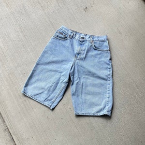 Puede incluir: Pantalones cortos de mezclilla azul claro con cierre de botón y cremallera. Los pantalones cortos tienen cinco bolsillos y un ajuste holgado.