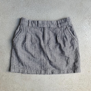 May include: A gray herringbone mini skirt with a waistband, belt loops, and front pockets. The skirt has a zipper and button closure. The fabric has a subtle vertical stripe pattern.