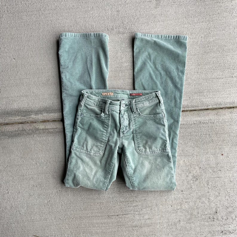 May include: A pair of green corduroy pants with a wide leg and a button fly. The pants have two large pockets on the front and a small pocket on the back.