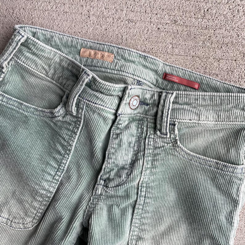 May include: A pair of light green corduroy pants with a straight leg and a zipper fly. The pants have a faded look and are made of a soft, comfortable fabric.