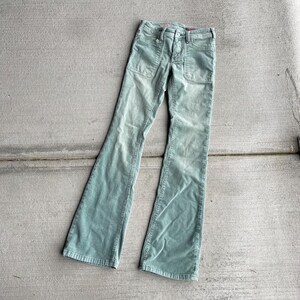 May include: A pair of light green corduroy bell bottom pants with a button fly and two patch pockets on the front.