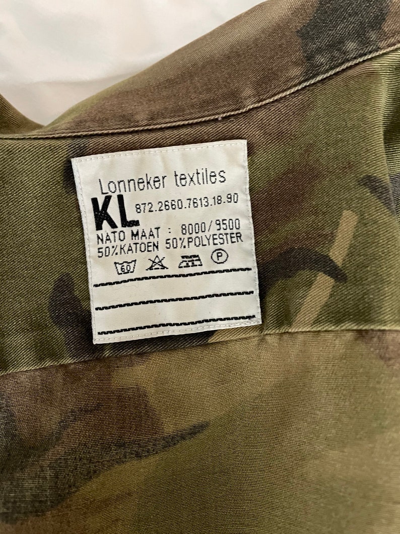 Może przedstawiać: Biała metka z czarnym tekstem, kt&oacute;ry brzmi "Lonneker textiles KL 872.2660.7613.18.90 NATO MAAT: 8000/9500 50% KATOOEN 50% POLYESTER" z symbolami instrukcji prania.