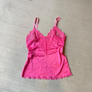 May include: A pink satin camisole with lace trim. The camisole has adjustable straps and a sweetheart neckline.