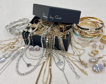 May include: A selection of gold and silver jewellery, including necklaces, bracelets, earrings, and rings. Some pieces feature gemstones and pearls. A black box, marked "Choice by Choi", is open and filled with necklaces and other items.