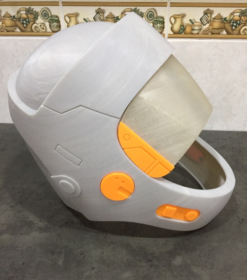 May include: A white helmet with orange accents and a clear visor. The helmet has a rounded top and a chin strap.