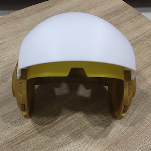 May include: A white helmet with gold accents and a yellow visor. The helmet is open and the visor is down.