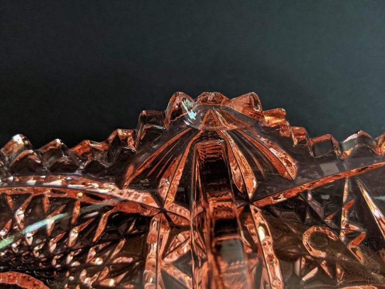 Puede incluir: Un cuenco de vidrio rosa vintage con un dise&ntilde;o geom&eacute;trico. El cuenco tiene un patr&oacute;n de estrella y est&aacute; hecho de vidrio transparente con un tinte rosa.