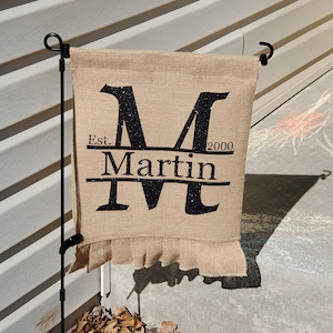 May include: A burlap garden flag with a black glitter letter "M" and the text "Est. 2000 Martin" in black.