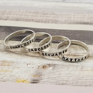 May include: Four silver rings with the names "Charlotte", "Caroline", "Benjamin", and "Matthew" engraved on them.