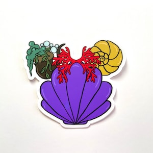 May include: A purple seashell with a red coral design, a brown seaweed plant, and a yellow seashell. The seashells are a popular theme for home decor and crafts.