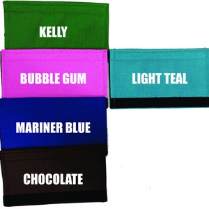 May include: Five different colored fabric wallets with black trim. The wallets are labeled "Kelly", "Bubble Gum", "Light Teal", "Mariner Blue", and "Chocolate".