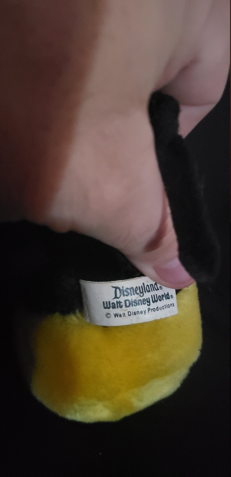 May include: Yellow plush toy with a black face and a white tag that reads "Disneyland Walt Disney World &copy; Walt Disney Productions".